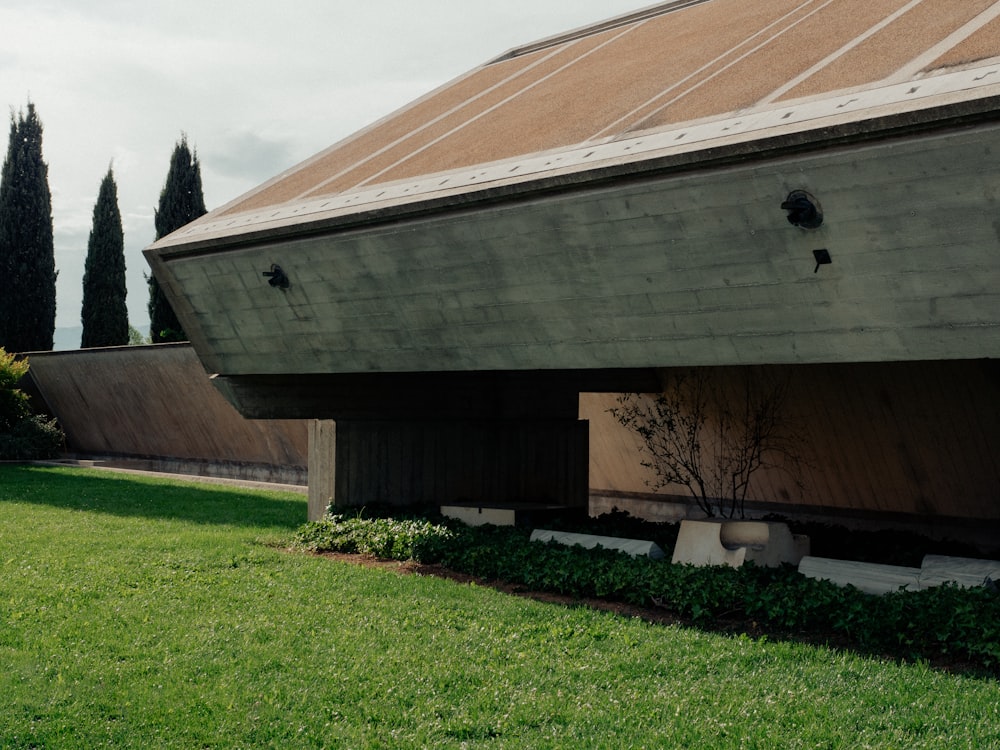 a building with a roof and a green lawn in front of it