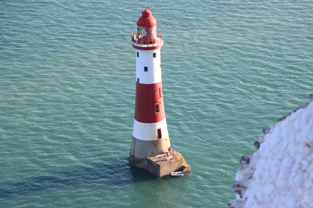 a red and white lighthouse in the middle of the ocean