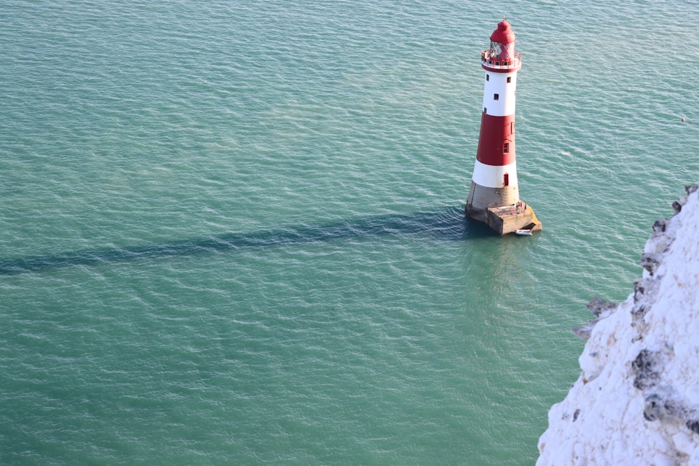 a red and white lighthouse in the middle of the ocean