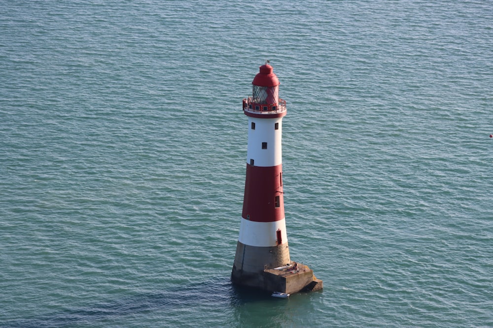 a red and white lighthouse in the middle of the ocean