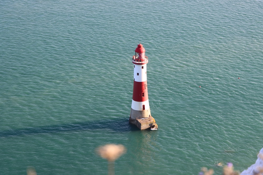 a red and white lighthouse in the middle of the ocean