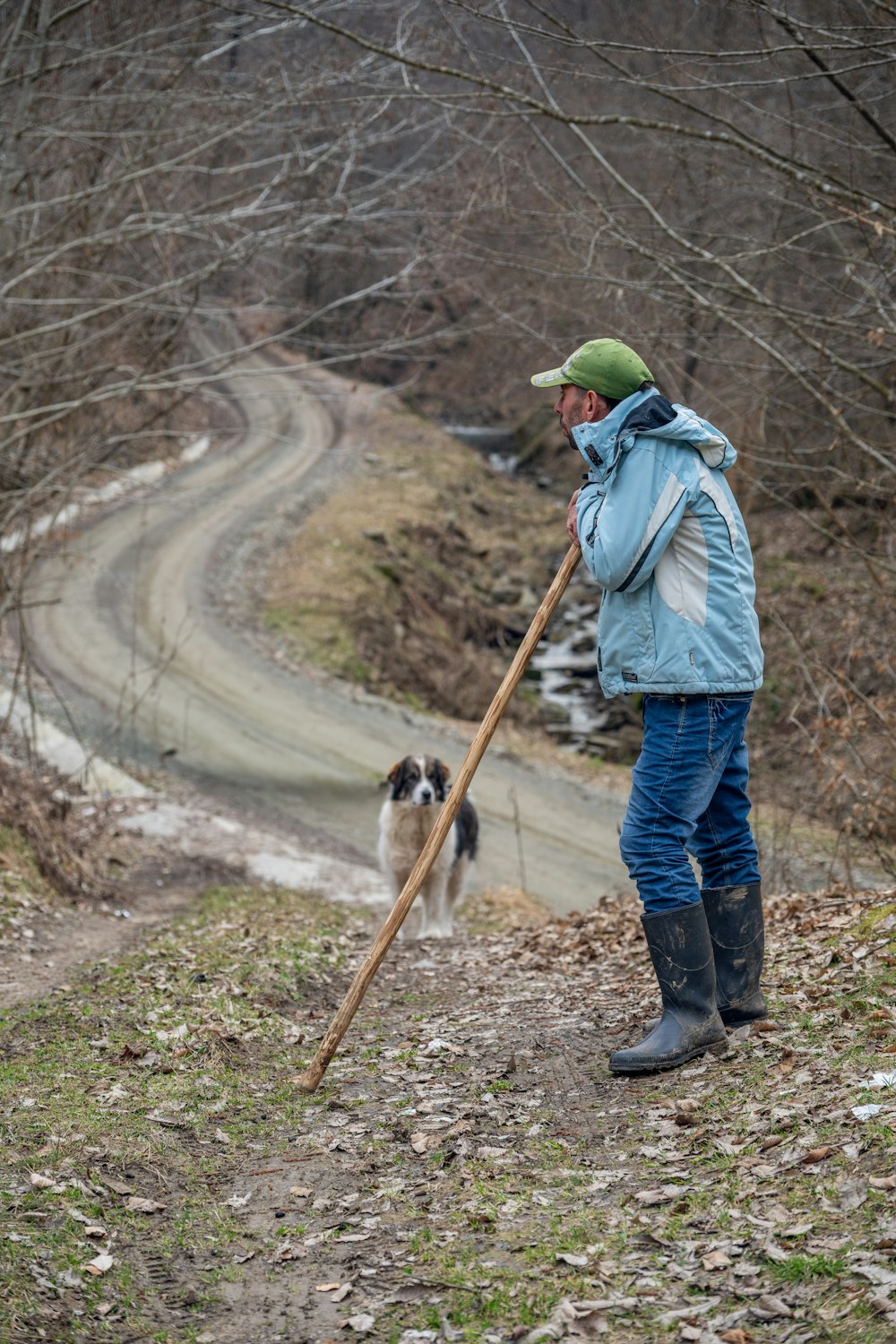 a man with a stick and a dog on a path