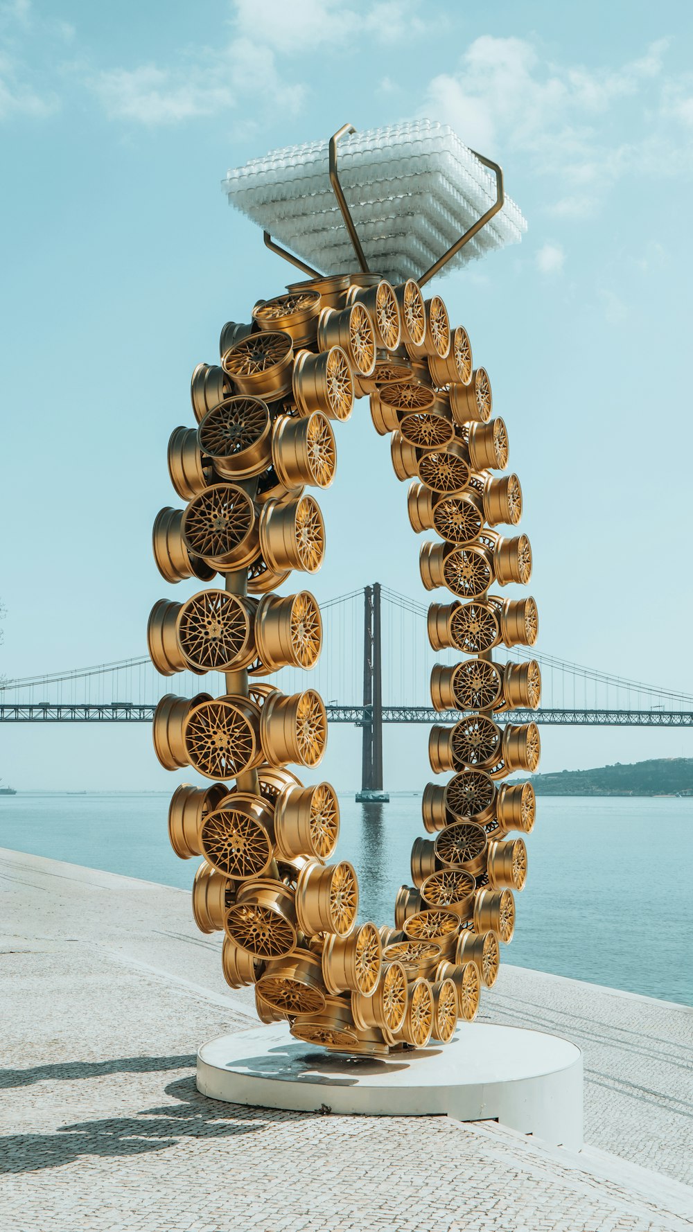 a sculpture made of gold wheels on a white pedestal