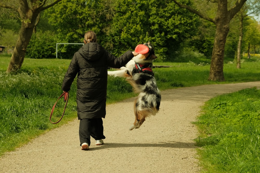 a woman walking a dog on a leash down a path