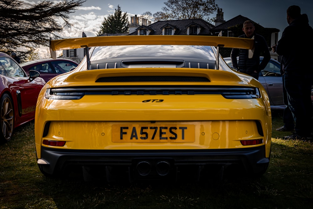 a yellow sports car parked next to other cars