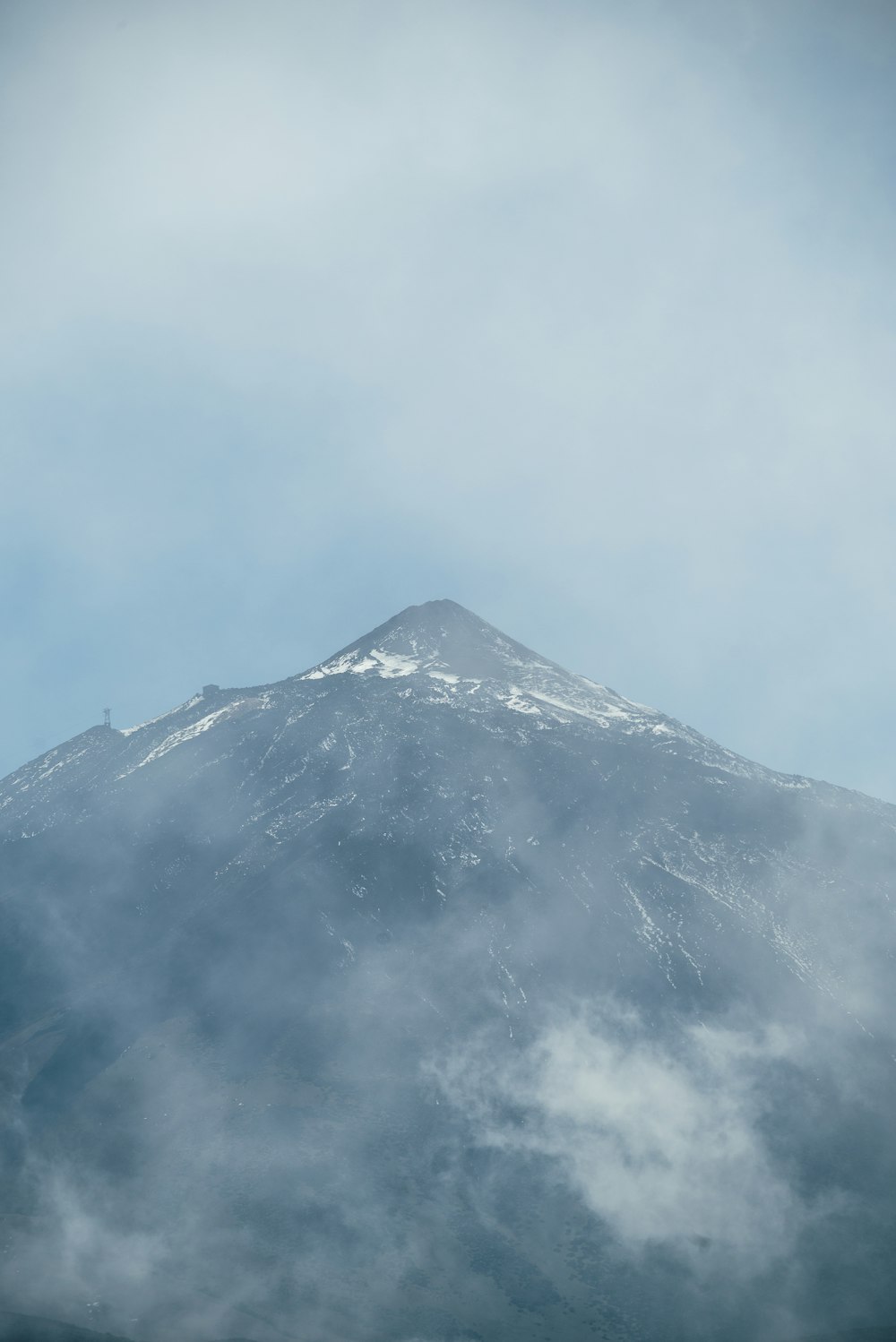 a very tall mountain covered in snow under a cloudy sky