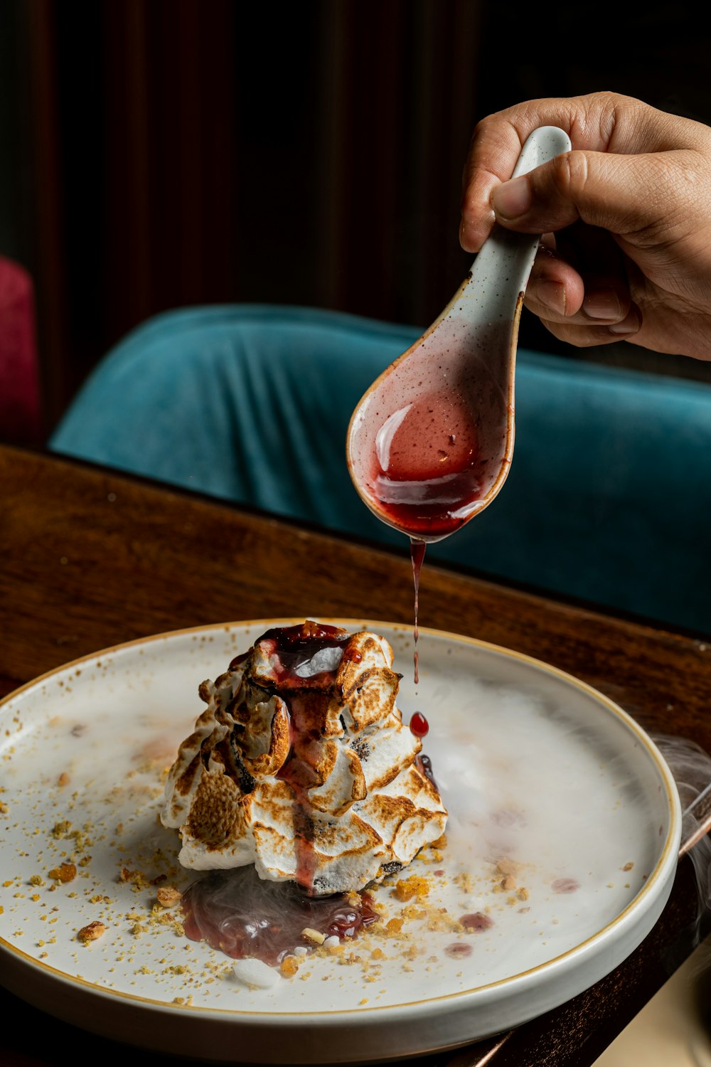 a person drizzling sauce onto a plate of food