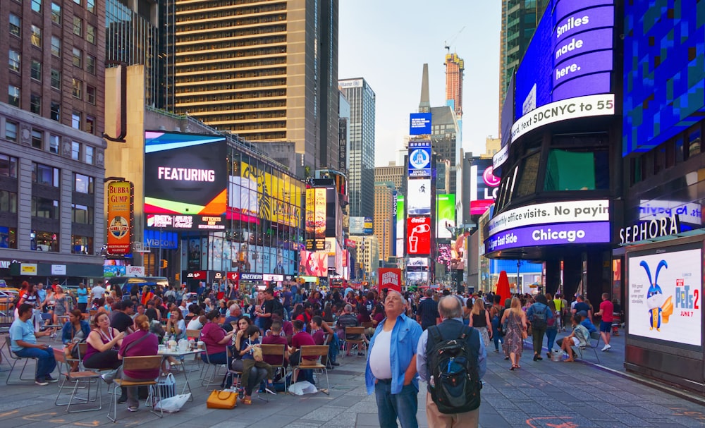 a crowd of people walking down a street next to tall buildings