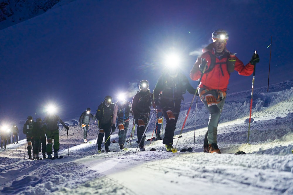 a group of people walking up a snow covered slope at night