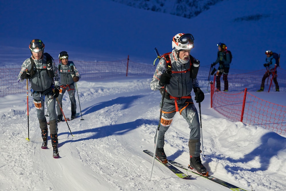 a group of people riding skis down a snow covered slope