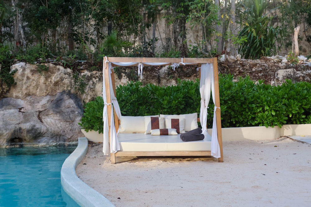 a bed sitting on top of a sandy beach next to a pool