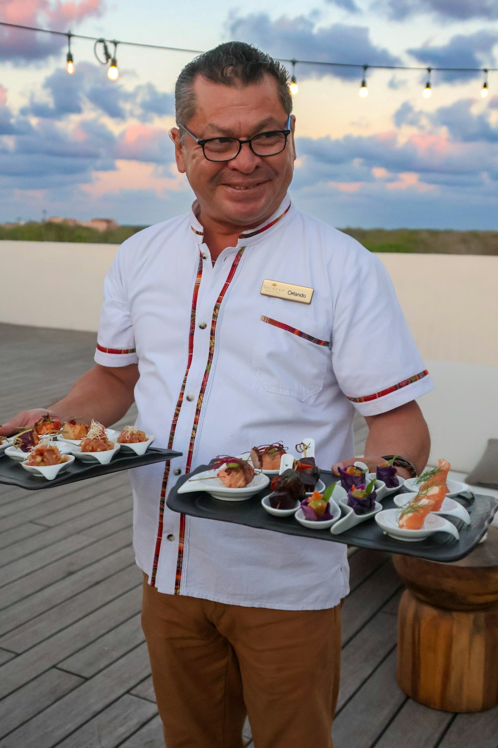 a man holding a tray of food on a deck