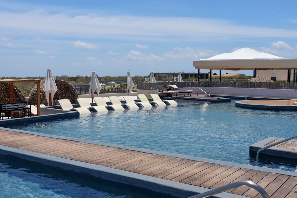 a large swimming pool with lounge chairs and umbrellas