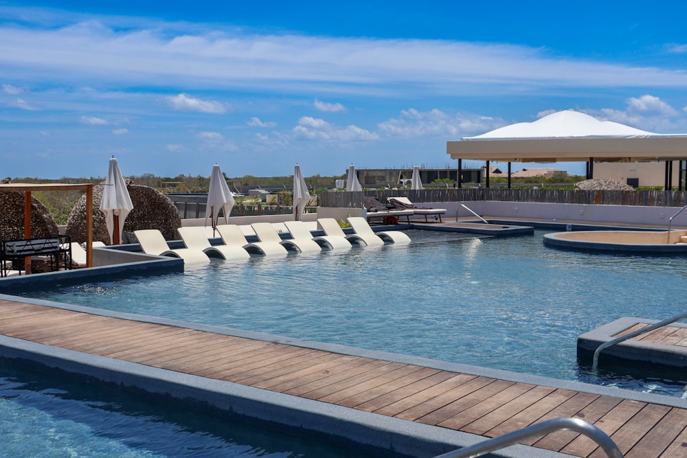 a large swimming pool with lounge chairs and umbrellas