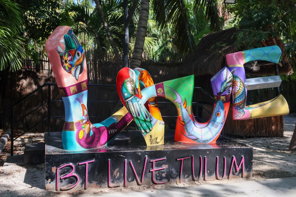 a sign that says bt live tulum in front of some trees