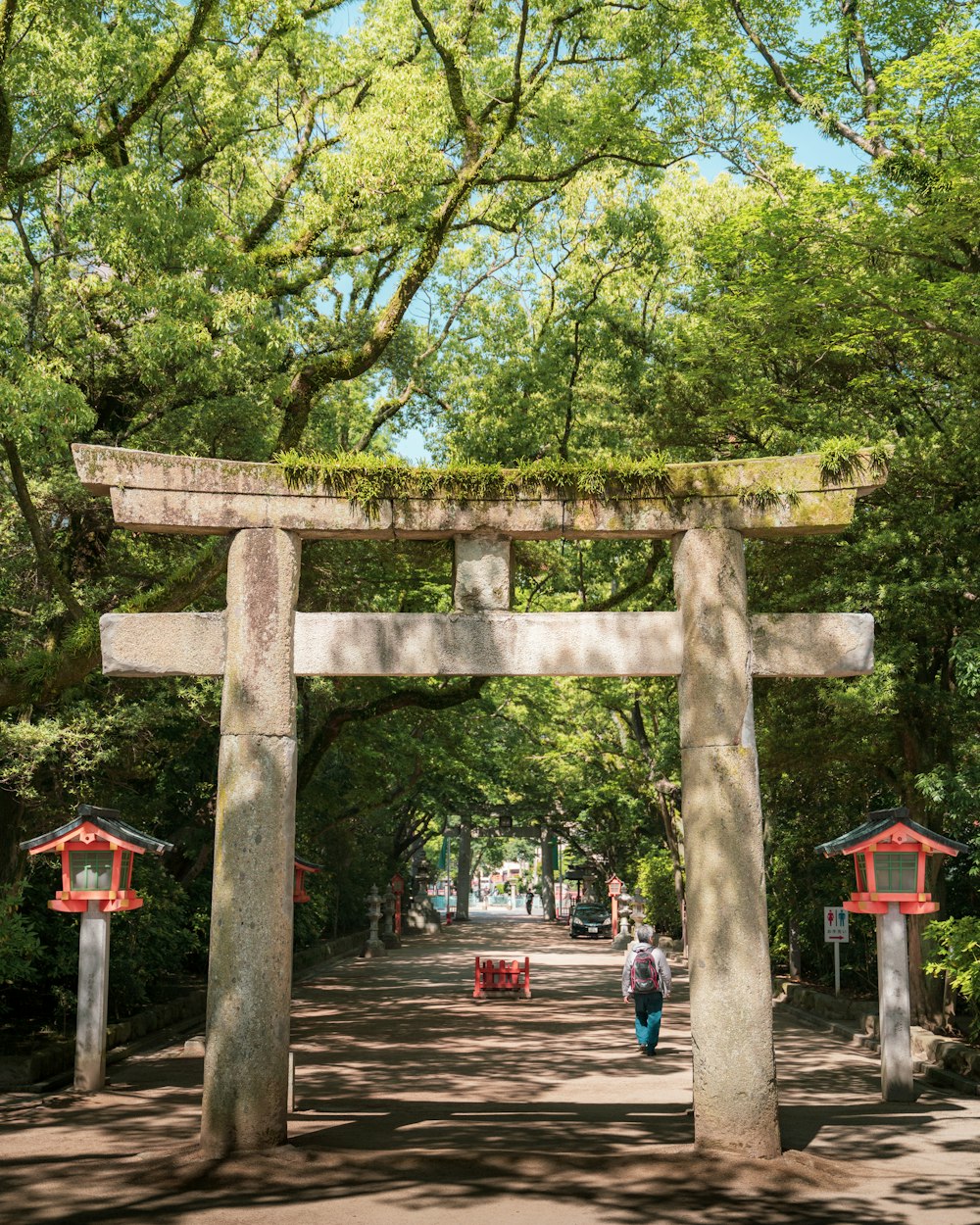 a person walking under a large stone arch in a park