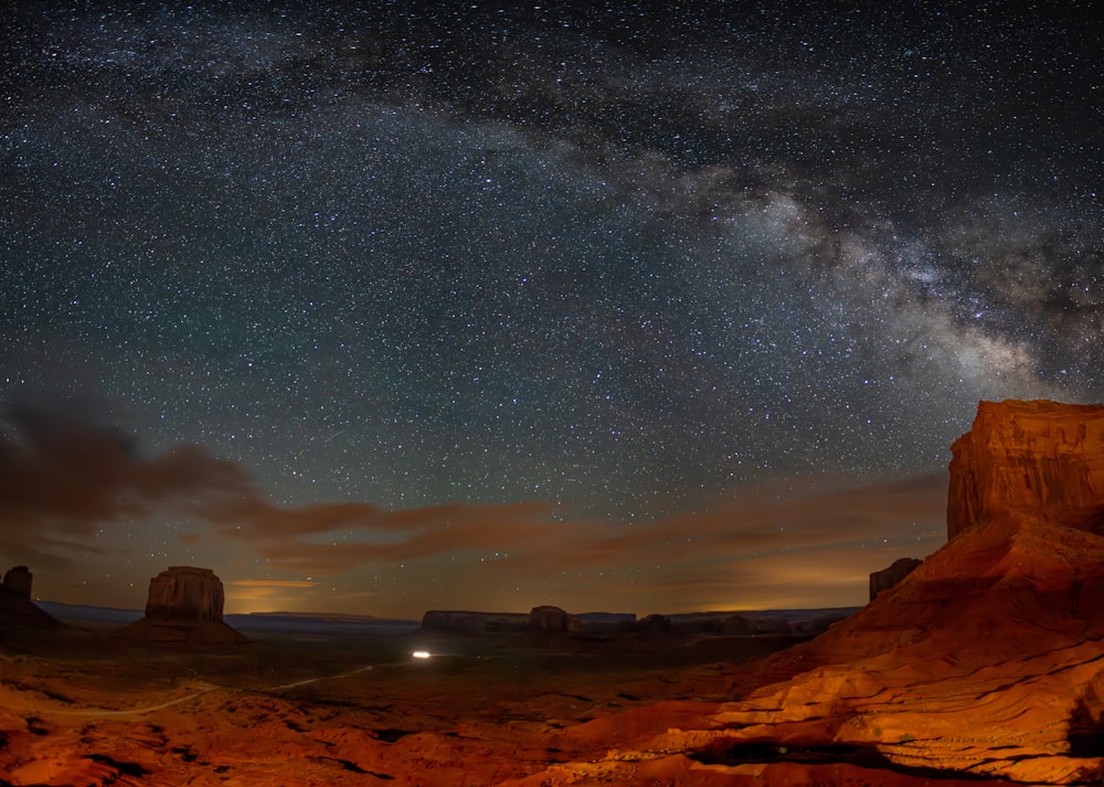 the night sky is filled with stars above a desert landscape