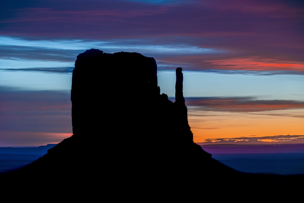 a tall rock formation in the middle of a sunset