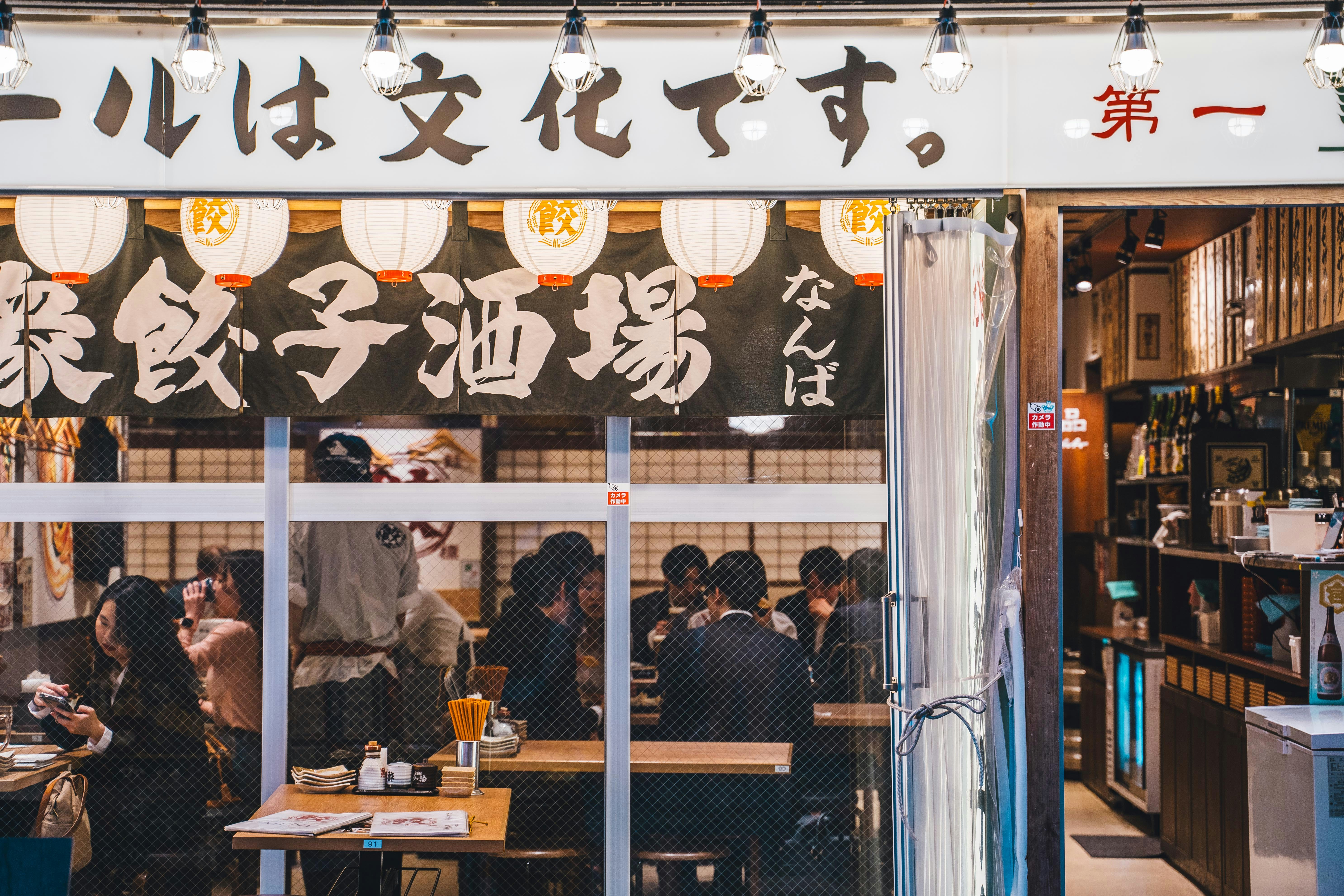 a group of people sitting at a table in front of a restaurant, 