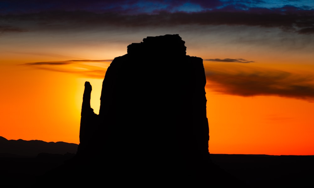 the sun is setting behind a rock formation