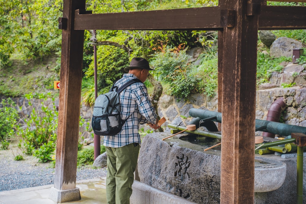 a man with a backpack standing under a wooden structure