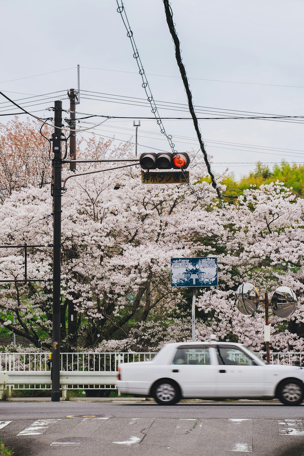 a white car driving down a street next to a traffic light