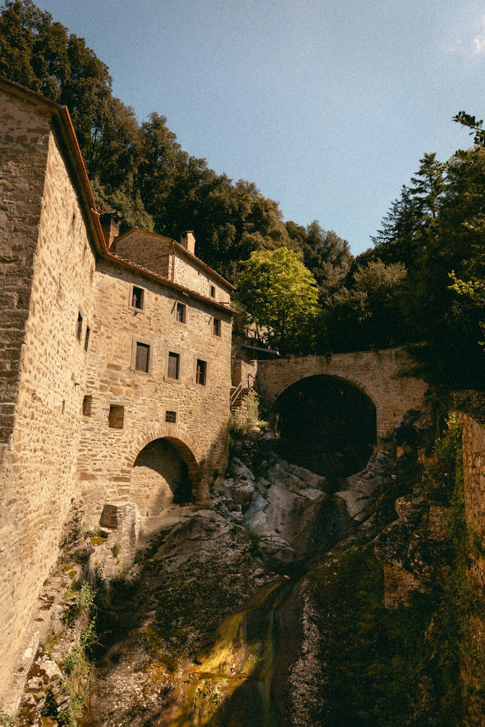 a stone bridge over a river next to a stone building