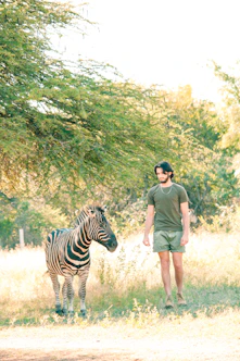 a man standing next to a zebra in a field conservation Cape Town Aysberg Karoo