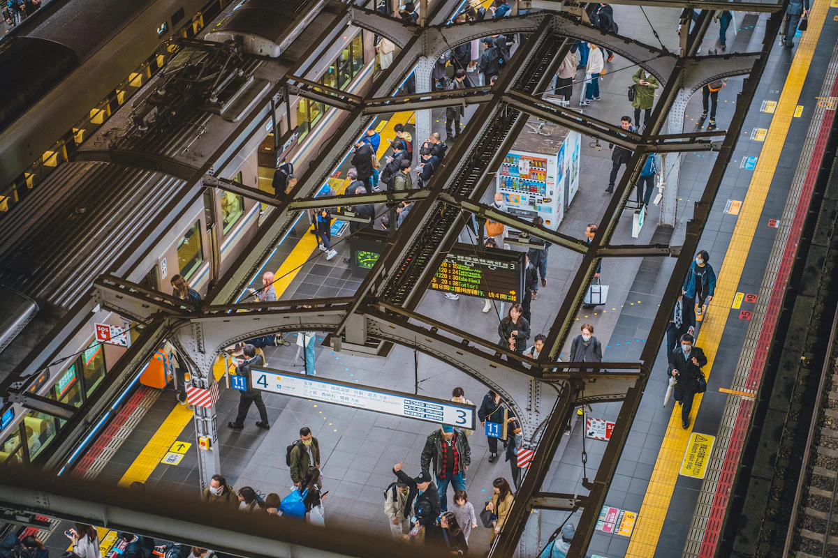 Platforms of Osaka Station from above, trains and travelers below the great roof