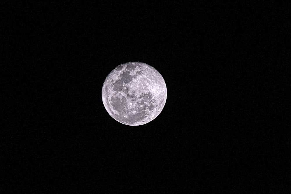 Une pleine lune est vue dans le ciel sombre