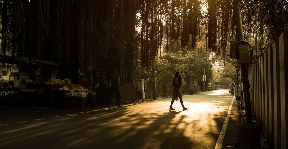 a person walking down a street next to tall trees