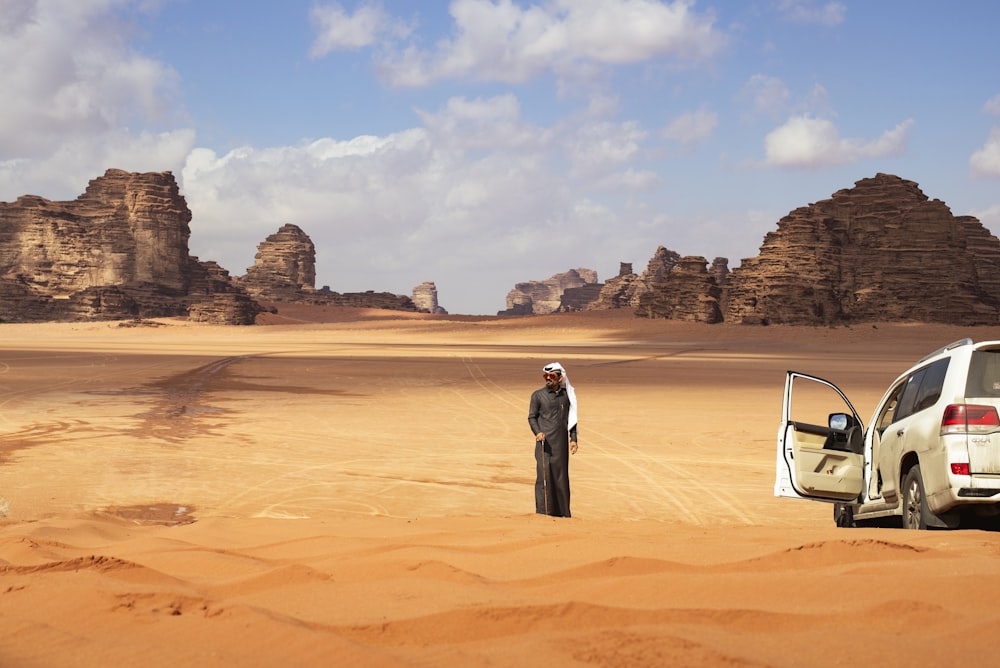 a man standing next to a car in the desert