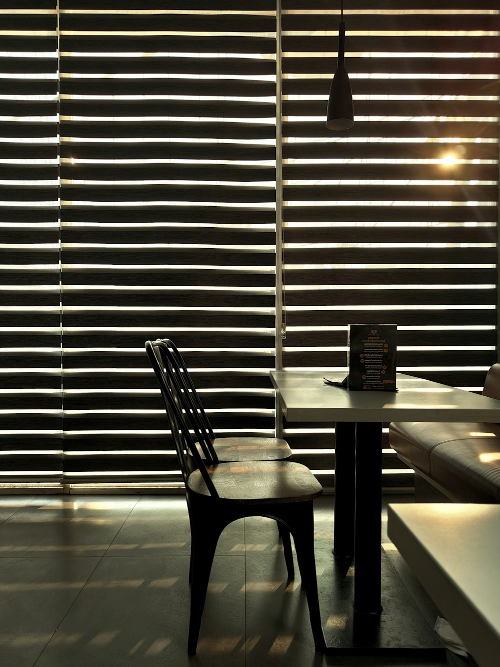 a chair and table in front of a window with blinds