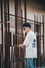 a man wearing a white oversized crew neck t-shirt standing next to a construction site