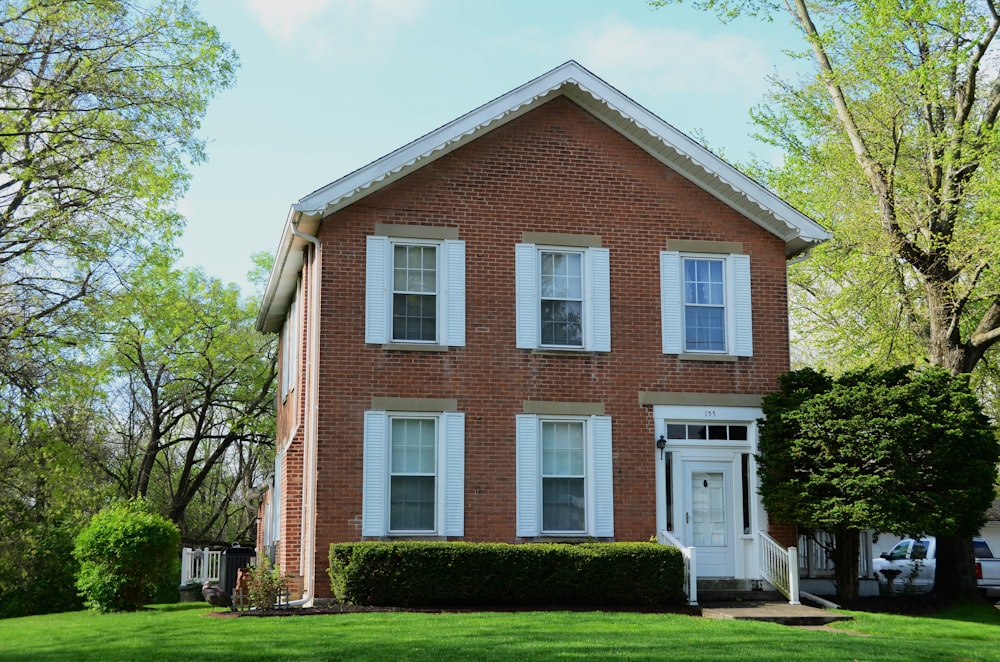 a red brick house with white shutters on a sunny day