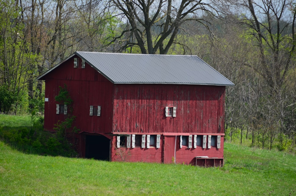 a red barn in a green field with trees in the background