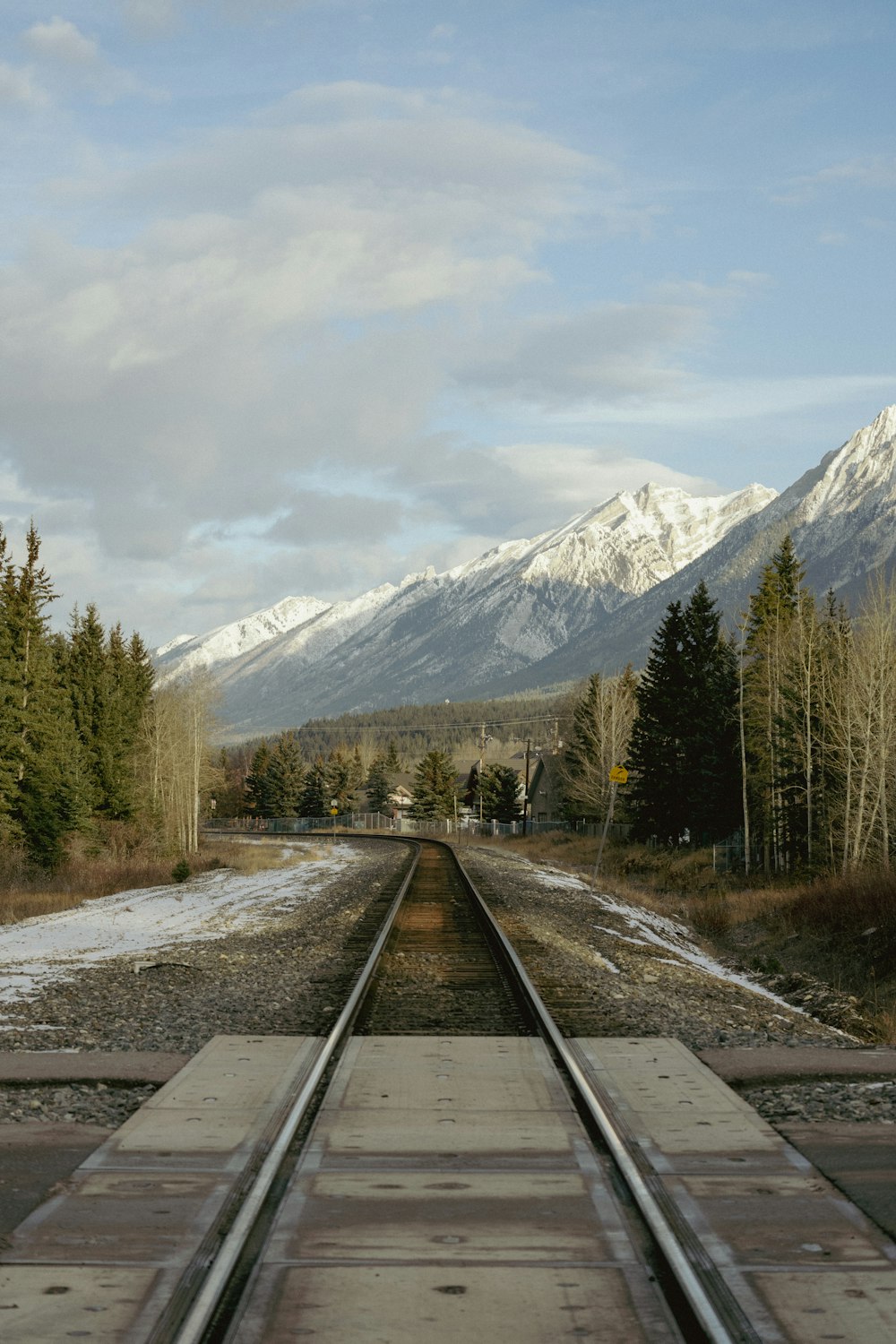 a train track with snow covered mountains in the background