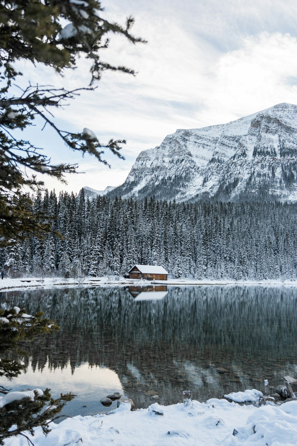 a lake surrounded by snow covered mountains and trees