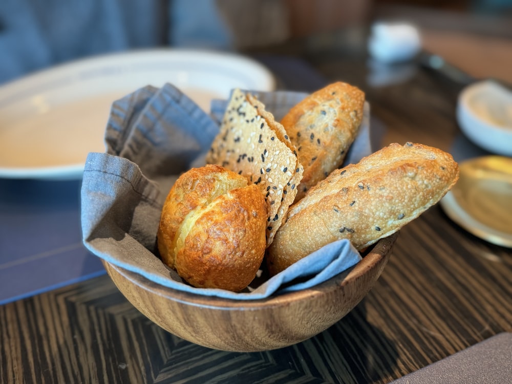 a bowl filled with loaves of bread on top of a table