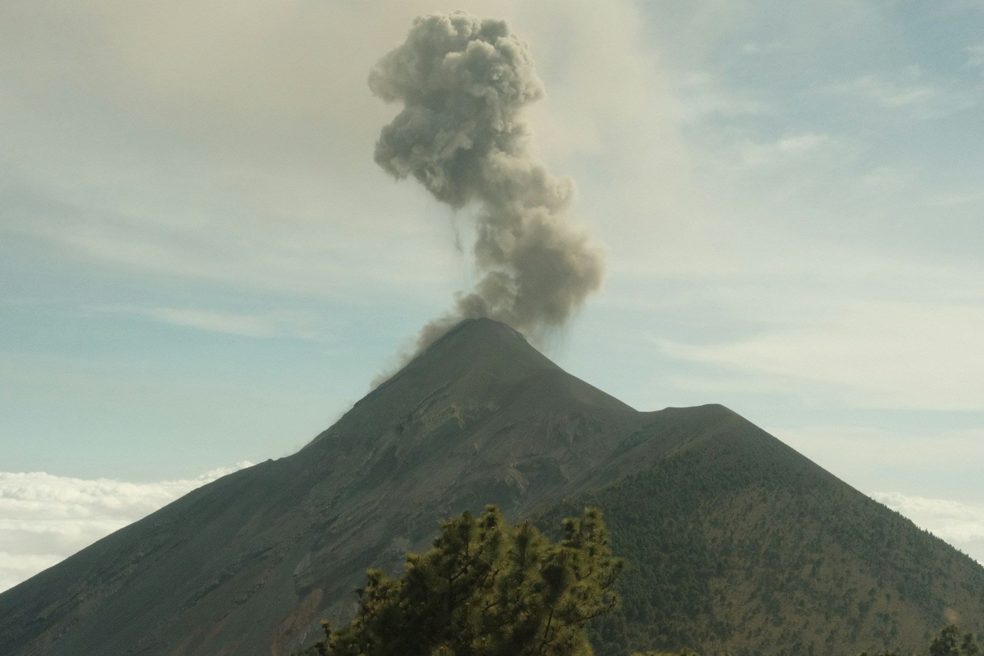 a large plume of smoke rising from the top of a mountain
