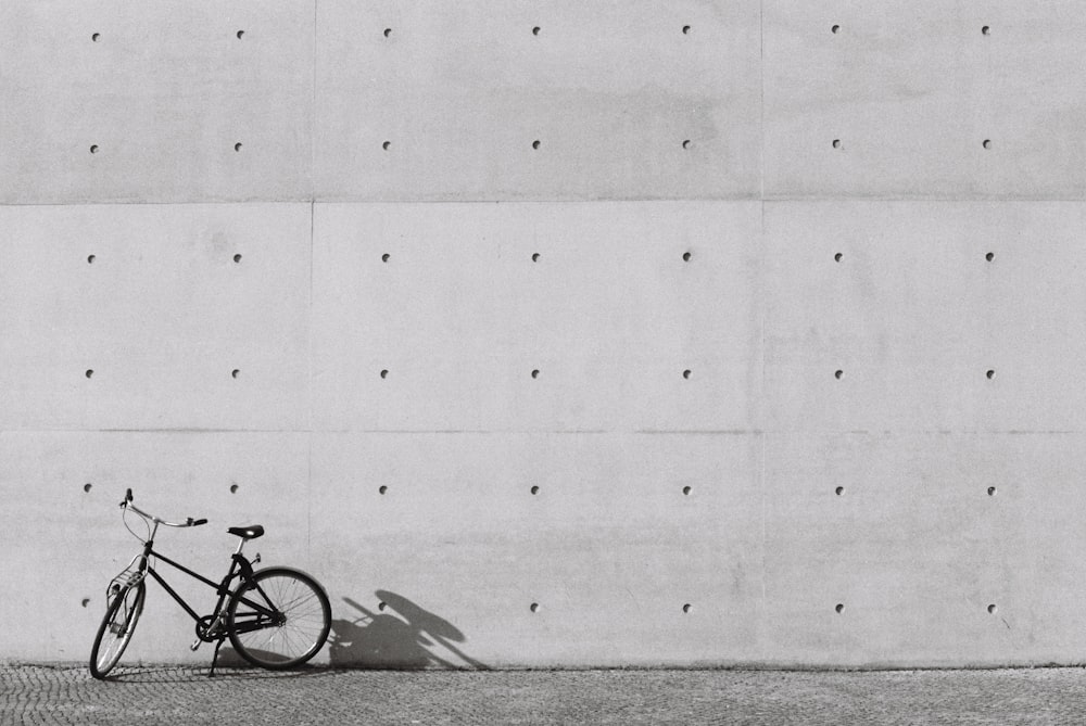 Una foto en blanco y negro de una bicicleta apoyada contra una pared