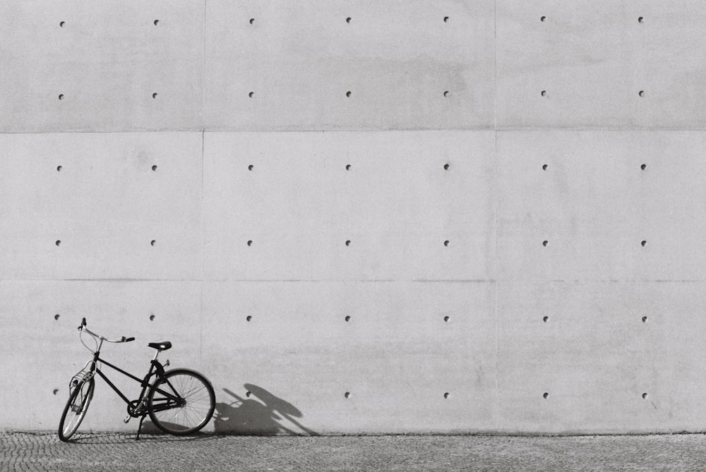 a black and white photo of a bike leaning against a wall