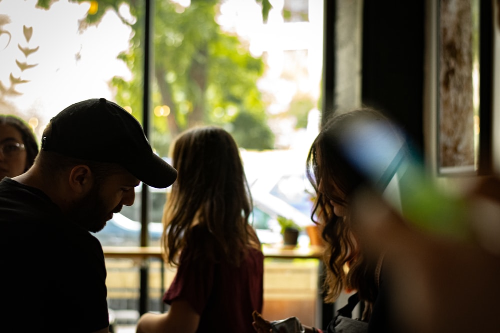 a man standing next to a little girl in front of a window