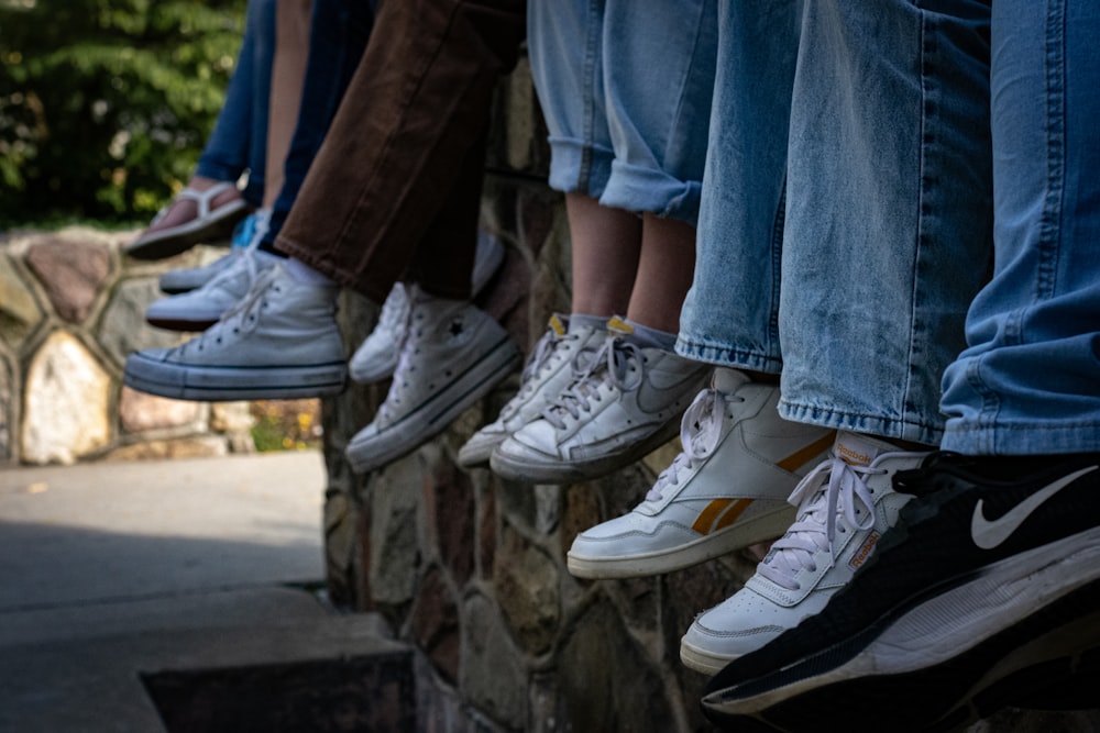 a group of people sitting on top of a stone wall