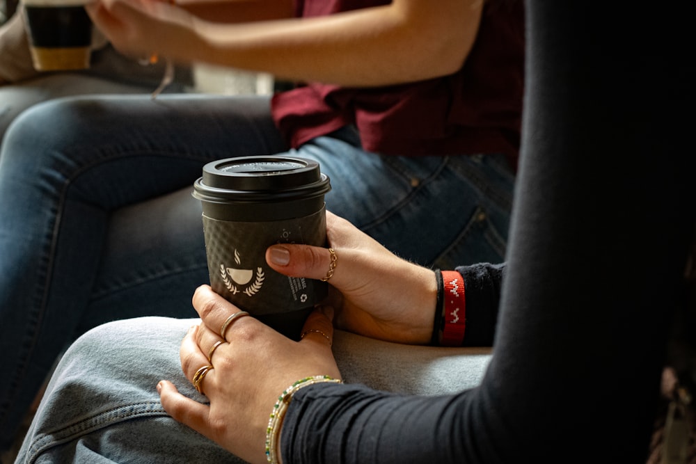 a woman holding a cup of coffee while sitting on a couch