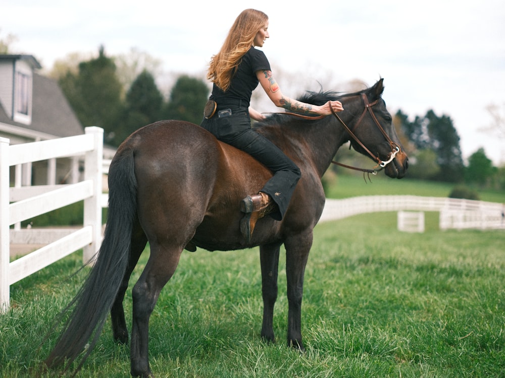 a woman riding on the back of a brown horse