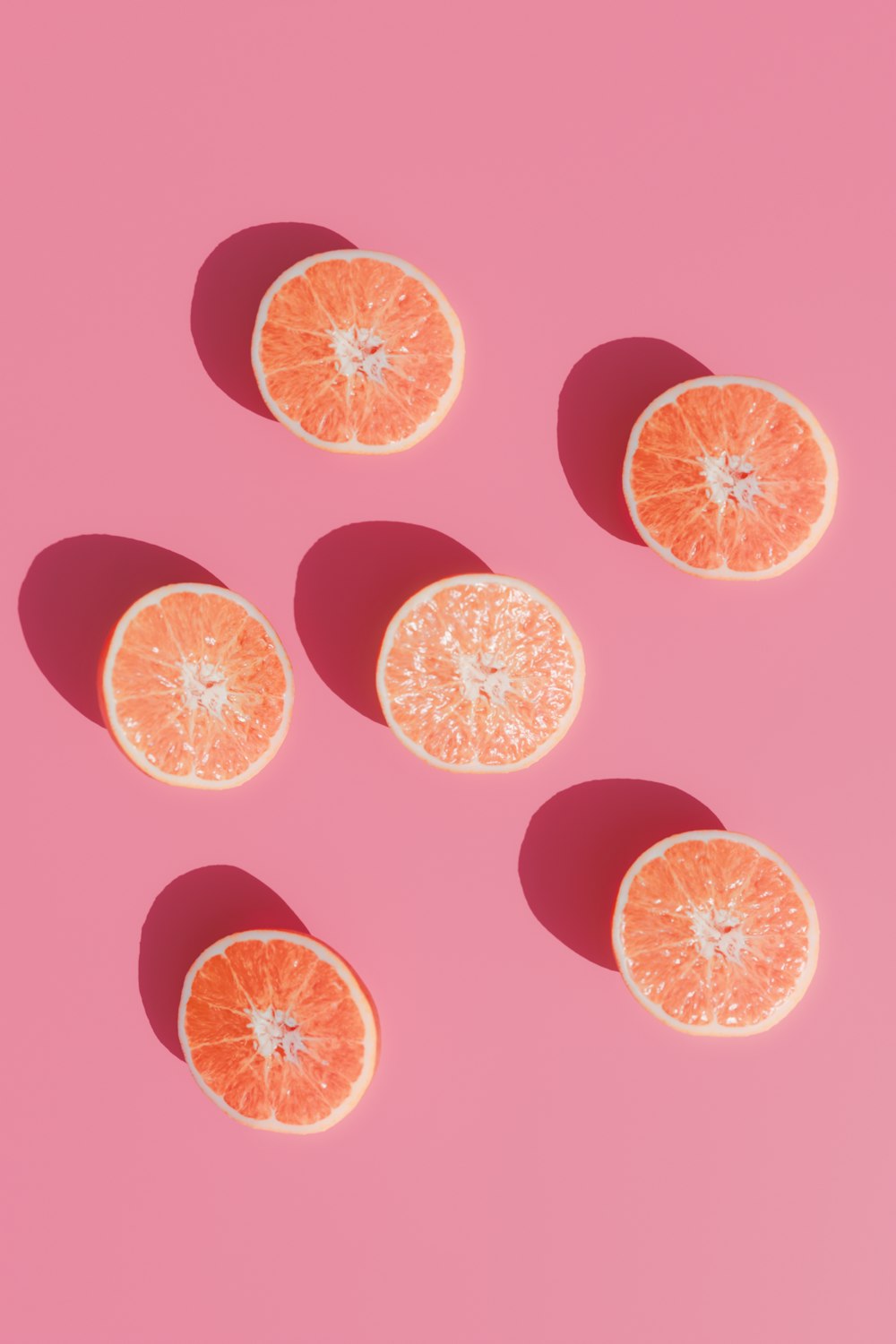 a group of oranges sitting on top of a pink surface