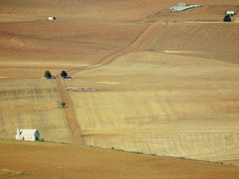 an aerial view of a farm field with a house in the distance