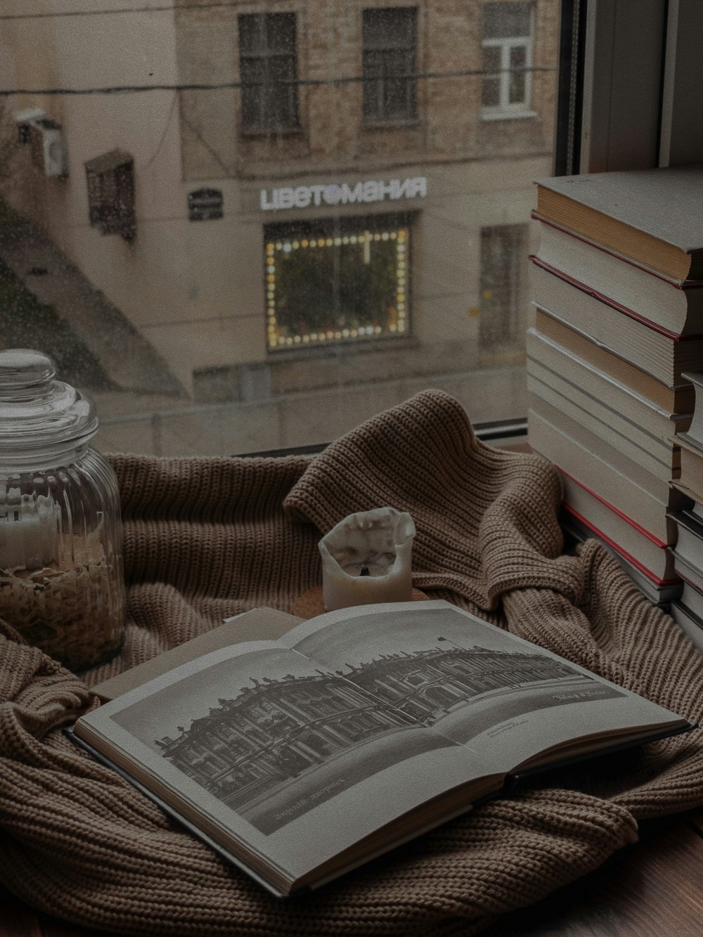 a stack of books sitting on top of a table next to a window