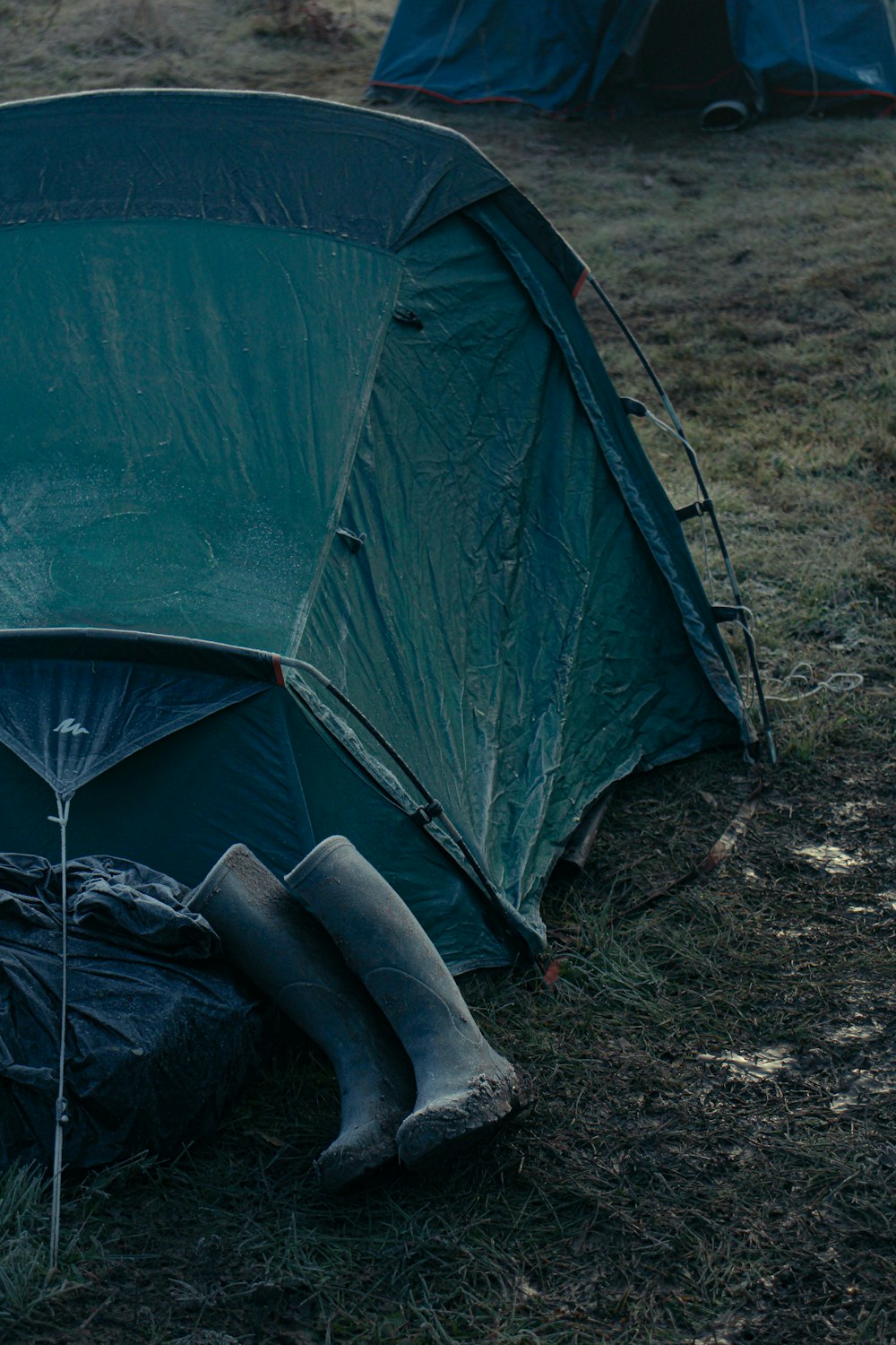 a tent is set up in a field with a pair of boots on the ground